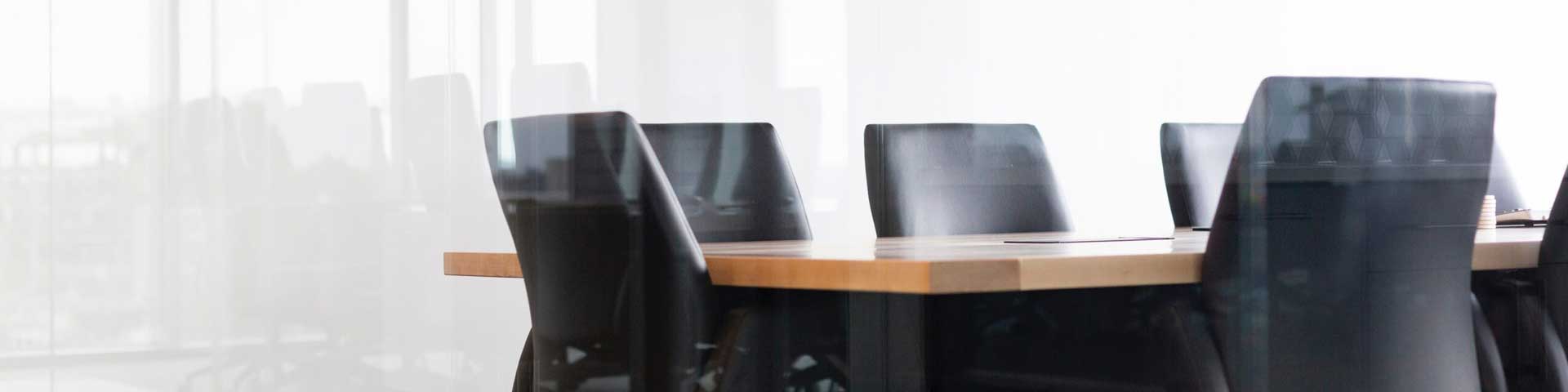 a modern meeting room with a wooden table surrounded by modern office chairs.